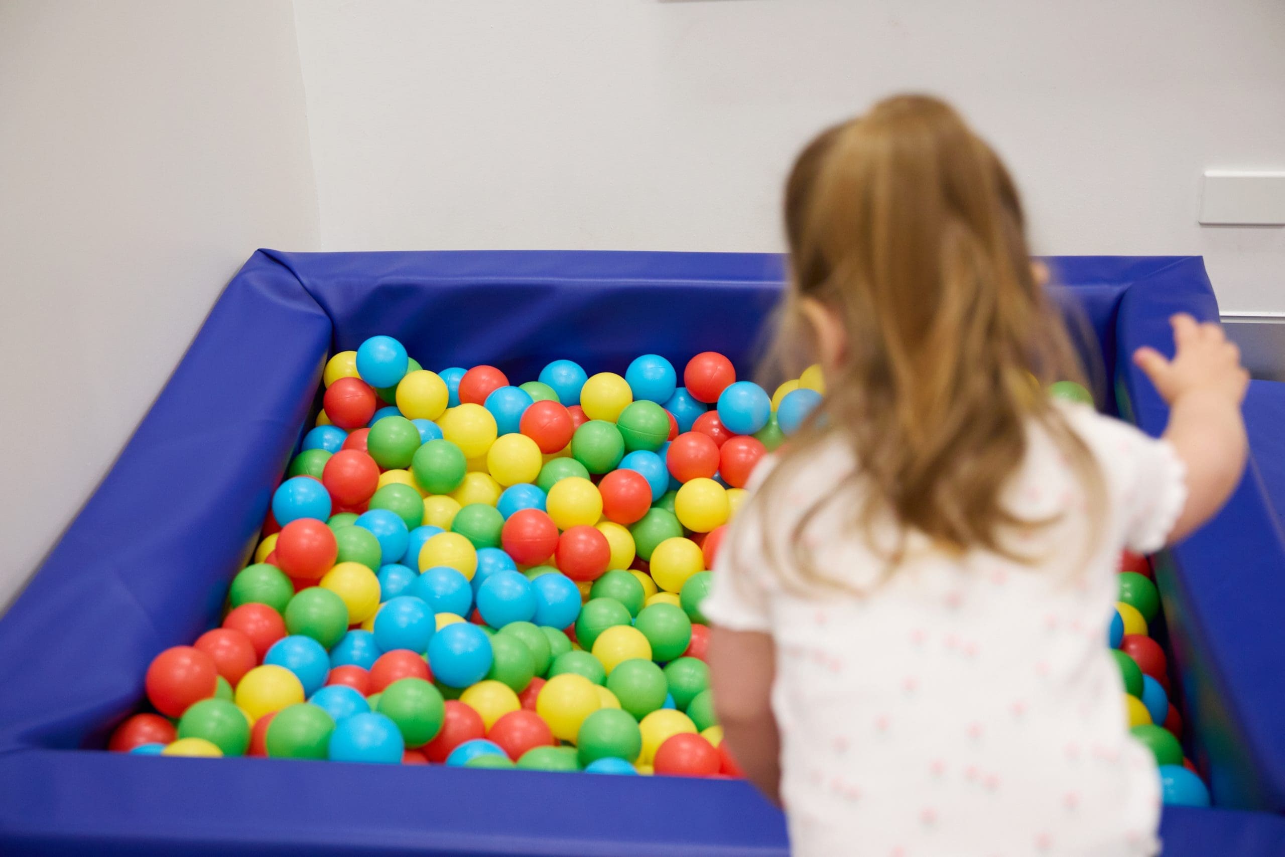 Child engaging in sensory play using a ball pit in a therapy space